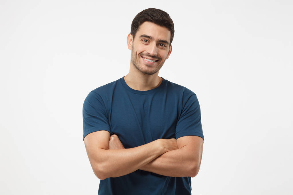 Retrato de chico guapo sonriente en camiseta azul de pie con brazos cruzados aislados sobre fondo gris
 - Foto, imagen