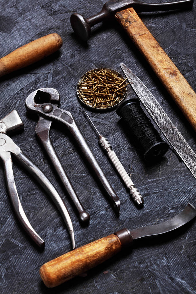 Conjunto de ferramentas de sapateiro vintage alicates, garras, gancho de costura, martelo de sapateiro no fundo de madeira escura. Vista superior
 - Foto, Imagem