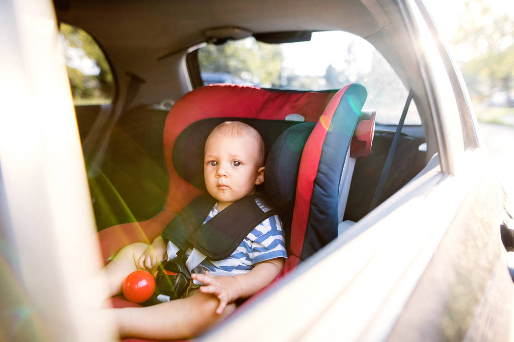 Kleine babyjongen zitten in de autostoel in de auto. - Foto, afbeelding