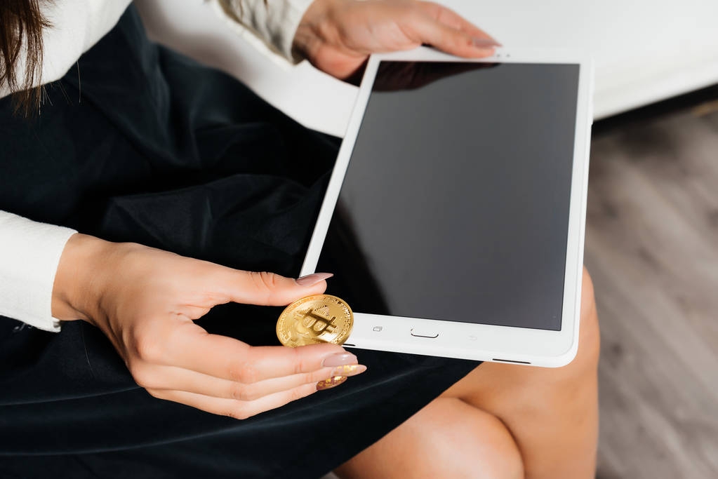 girl with a tablet in her hands. Girl hold a gold coin. Electronic money, Bitcoins, Crypto currency. - Photo, Image