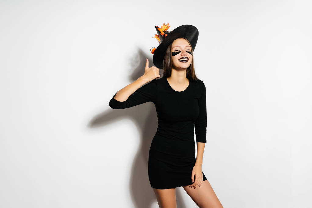 gülümseyen kız Halloween cadı güzel siyah elbise ve bir şapka ile sonbahar yaprakları. Kız Cadılar Bayramı partisinde. Tatil Cadılar Bayramı. - Fotoğraf, Görsel