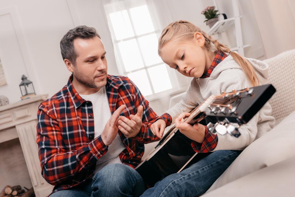 isä ja tytär soittamassa kitaraa
 - Valokuva, kuva