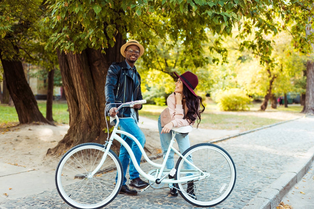 Счастливая пара, стоящая и опирающаяся на велосипед
 - Фото, изображение