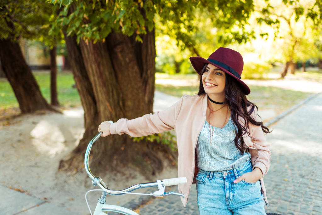 γυναίκα με καπέλο στέκεται με ποδήλατο  - Φωτογραφία, εικόνα
