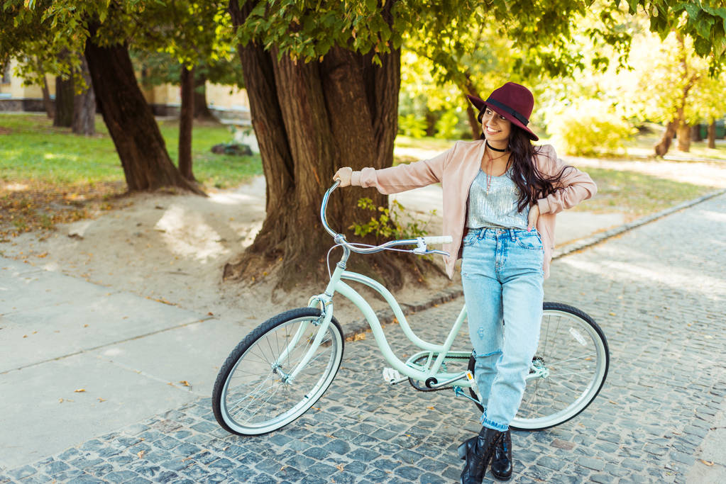Nainen hattu pystyssä polkupyörän kanssa
  - Valokuva, kuva