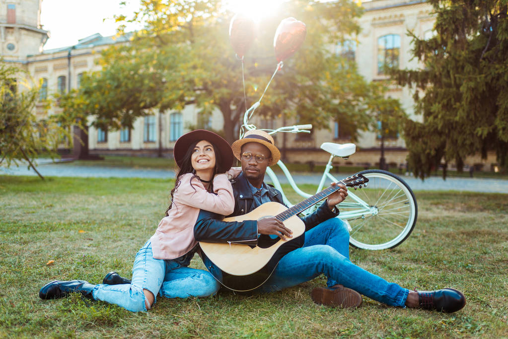 Пара сидить з гітарою в парку
 - Фото, зображення