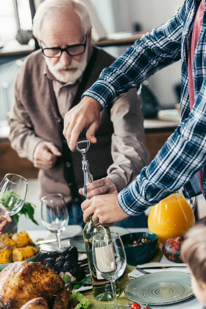 starszych i młodych mężczyzn otwarcie wina - Zdjęcie, obraz