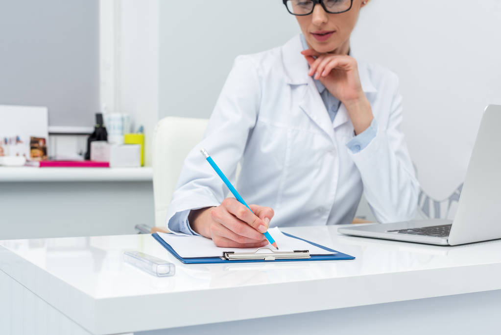 female doctor writing in clipboard - Photo, Image