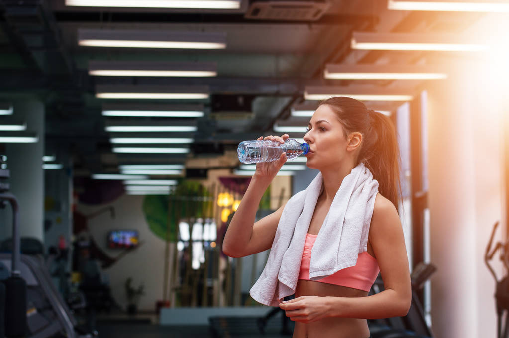 Girl drinking water in gym  - Photo, Image