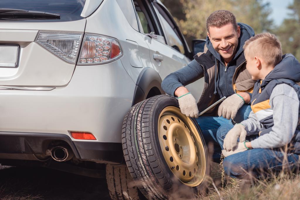 Apa és fia változó autó kerék - Fotó, kép