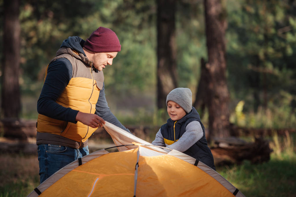 Pai e filho a montar tenda
 - Foto, Imagem