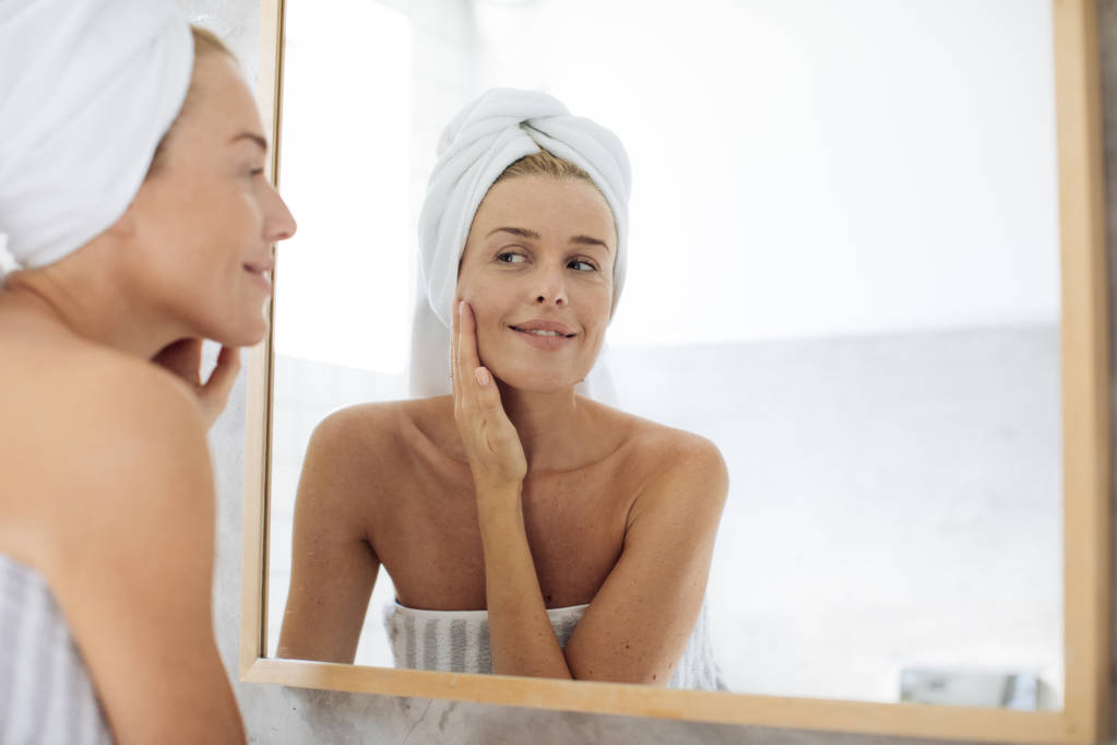 Mujer mirándose en espejo de baño
 - Foto, imagen
