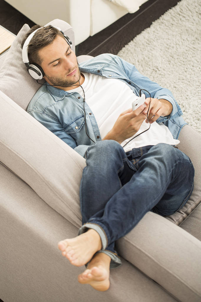 Веселый человек расслабляется на диване, слушает музыку
 - Фото, изображение