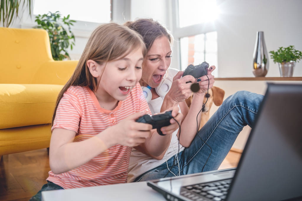 Anne ve kızı evde dizüstü bilgisayarda video oyunları oynarken - Fotoğraf, Görsel