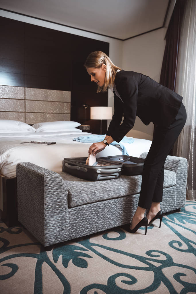 ビジネス女性はホテルの部屋でスーツケースを開梱 - 写真・画像