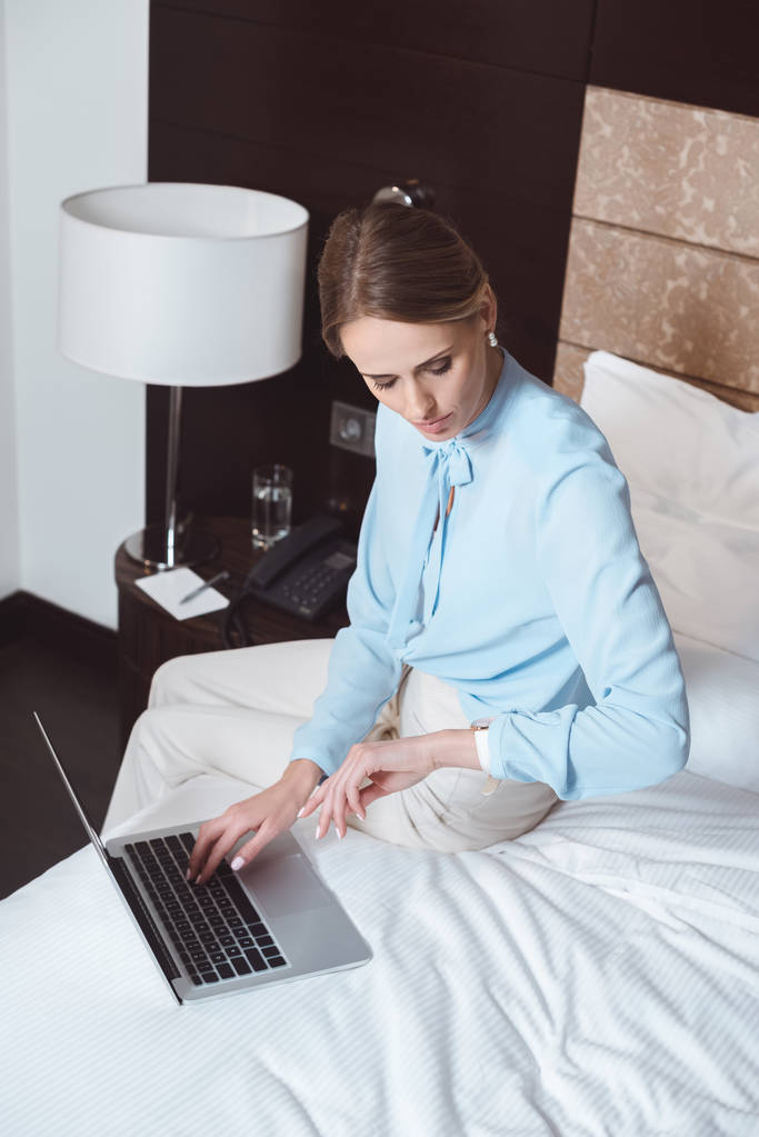 Femme d'affaires utilisant un ordinateur portable dans la chambre d'hôtel
 - Photo, image