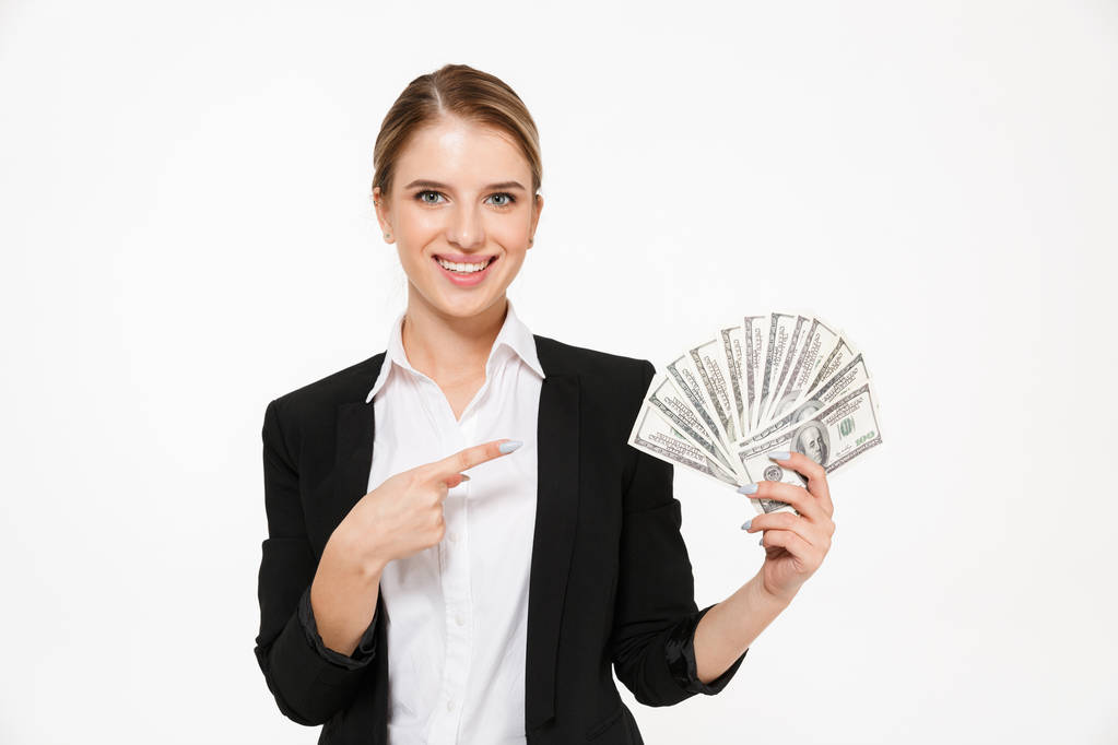 Sorrindo loira mulher de negócios segurando dinheiro e apontando em seu
 - Foto, Imagem