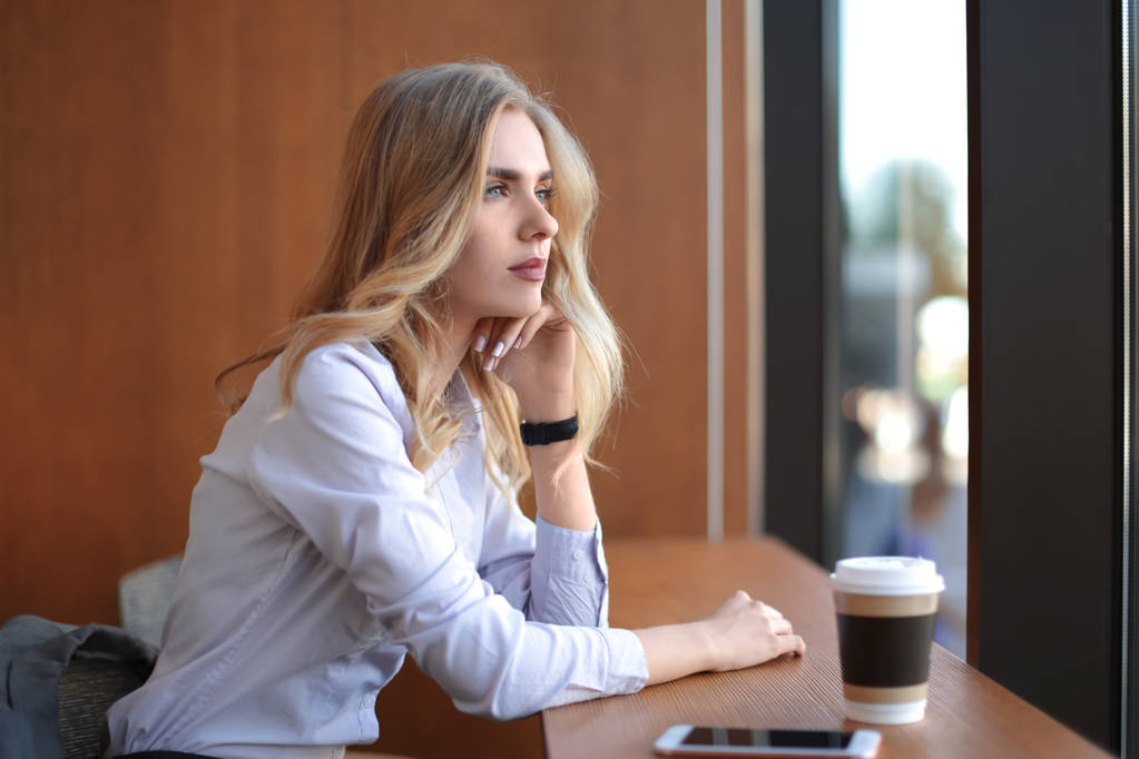 молодая женщина сидит за столом в кафе - Фото, изображение