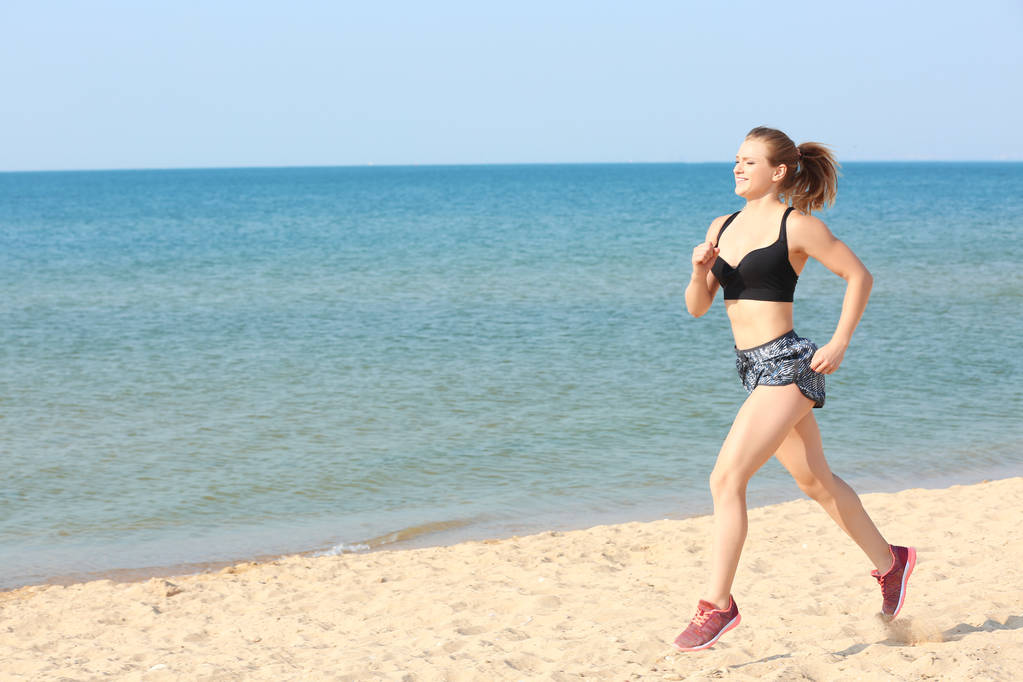 Jovem mulher esportiva correndo na praia do mar
 - Foto, Imagem
