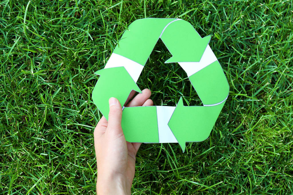 Kobieta trzyma symbol recyklingu przeciwko zielona trawa - Zdjęcie, obraz