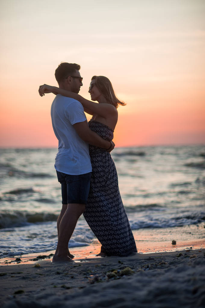 Пара влюбленных стоит, обнявшись на берегу моря
. - Фото, изображение