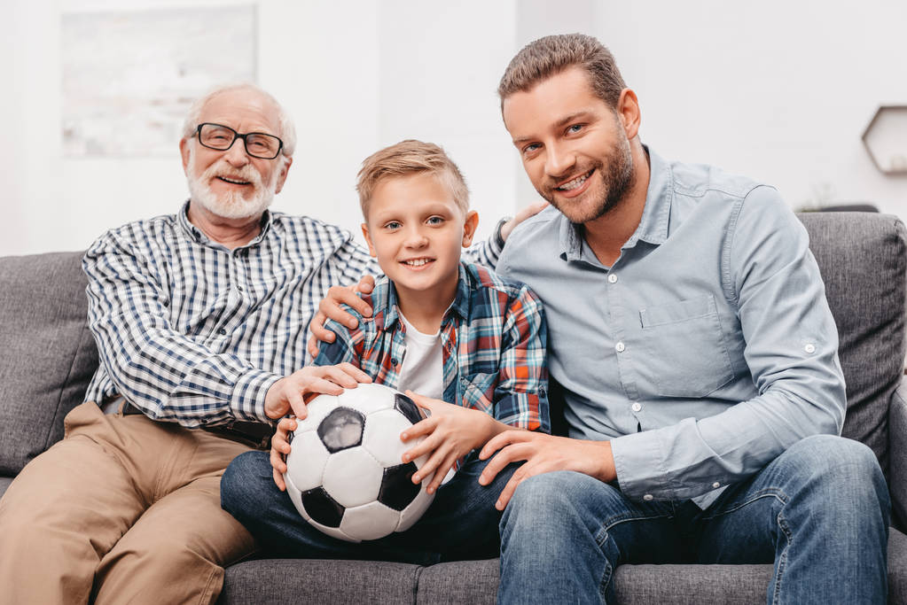 Семья сидит на диване с футбольным мячом
 - Фото, изображение