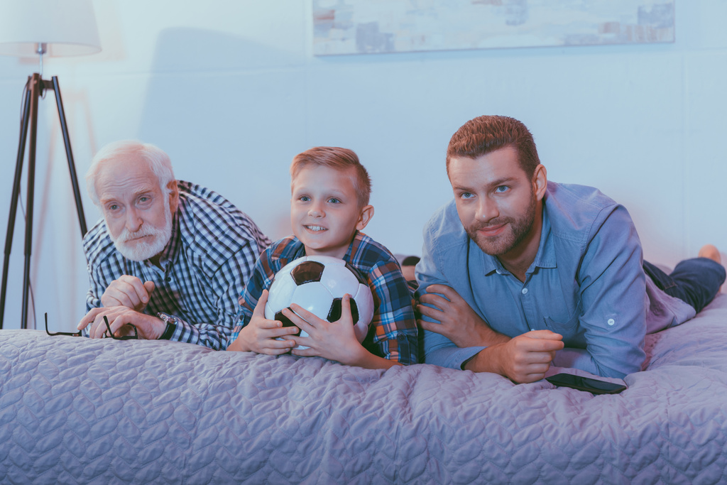 família assistindo futebol na cama
 - Foto, Imagem