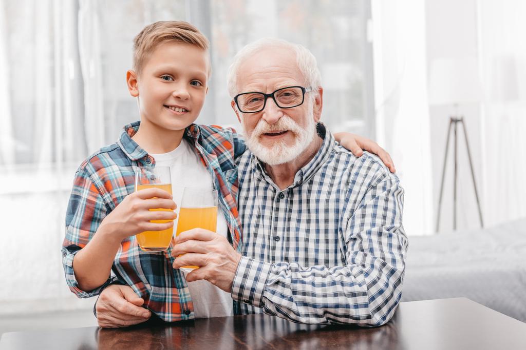 Fiú és nagyapja gazdaság narancslé - Fotó, kép