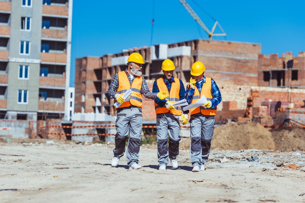 Drie werknemers in hardhats op de bouwplaats - Foto, afbeelding