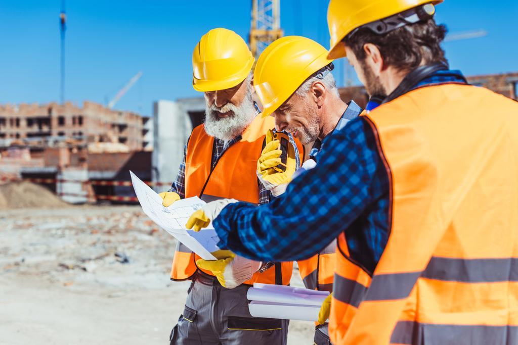 Trabalhadores da construção discutindo planos de construção
 - Foto, Imagem