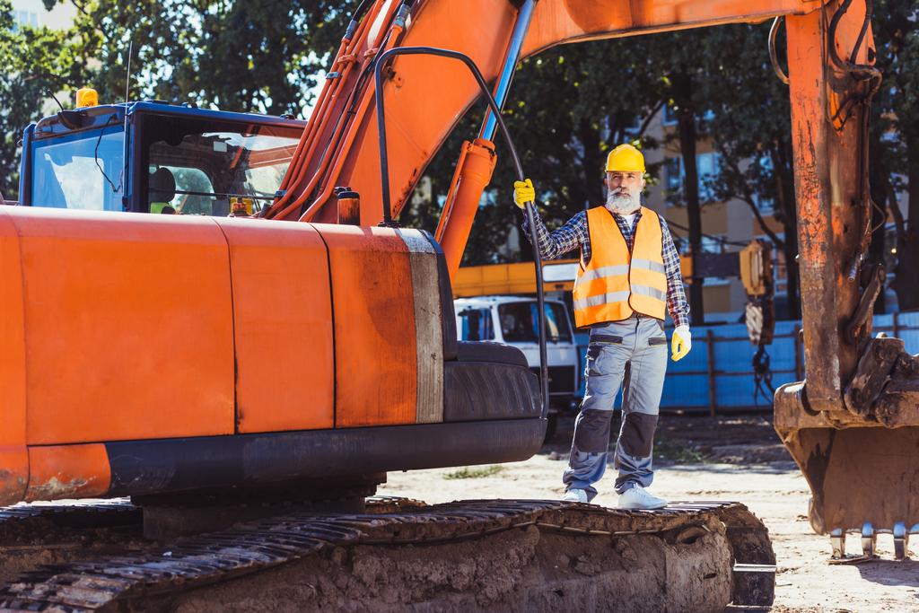 Trabajador de la construcción posando con excavadora
 - Foto, imagen