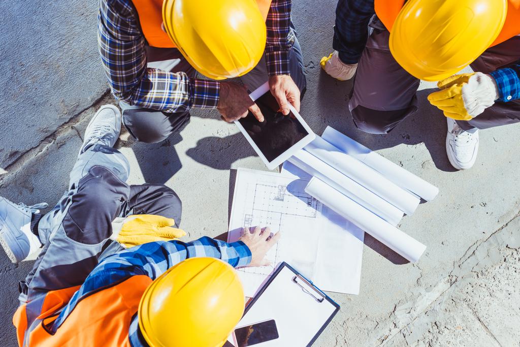 Rakennusalan työntekijät keskustelevat rakennussuunnitelmista
 - Valokuva, kuva