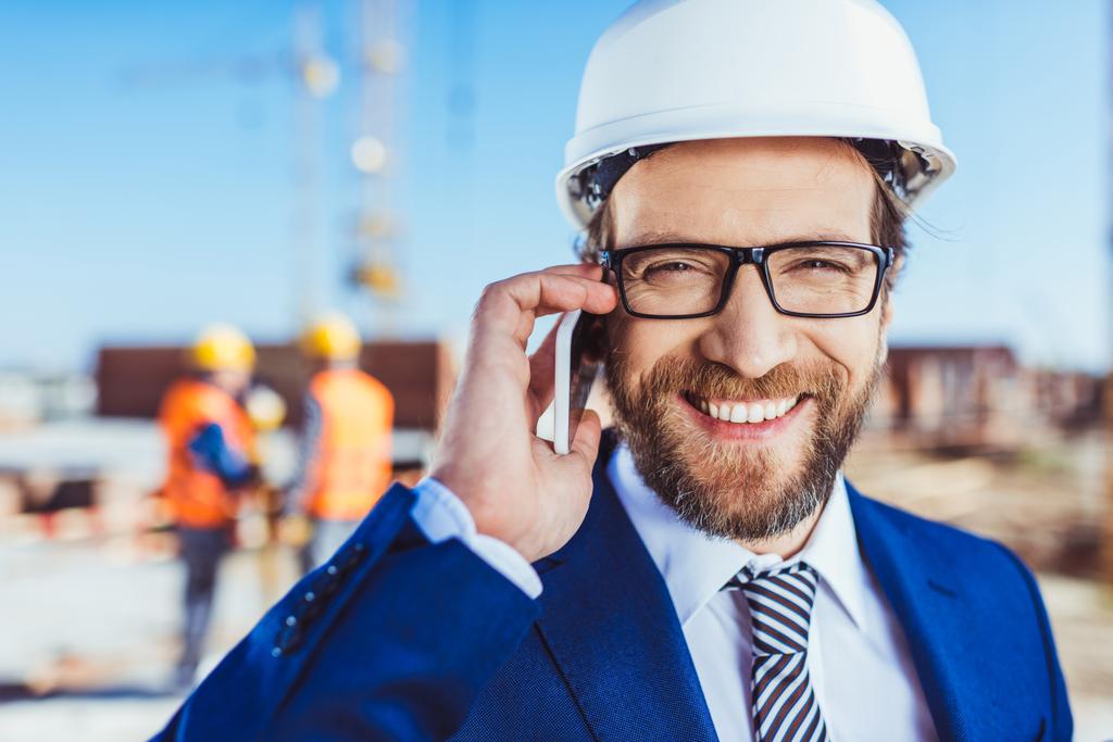Бизнесмен разговаривает по телефону на стройплощадке
 - Фото, изображение
