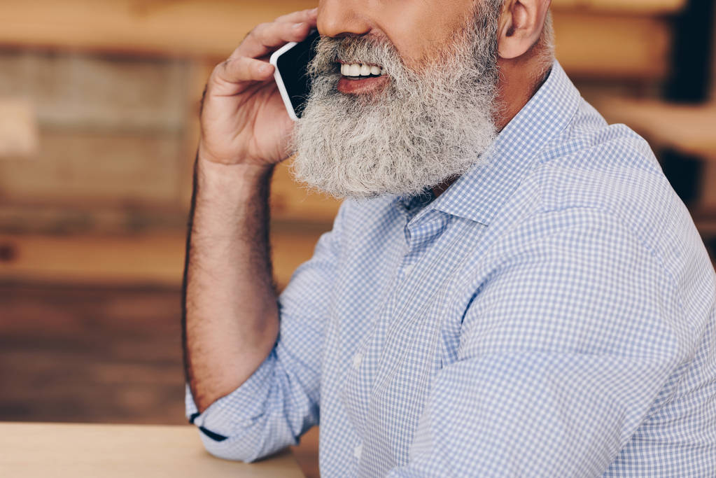 старший чоловік розмовляє по смартфону в кафе
 - Фото, зображення
