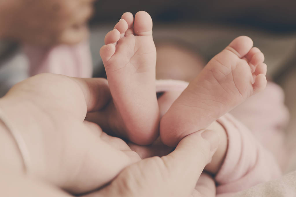 Der Fuß des Neugeborenen in der Hand der Mutter - Foto, Bild