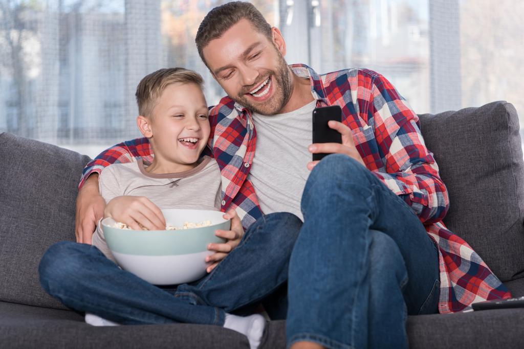 Отец и сын смотрят телевизор
  - Фото, изображение