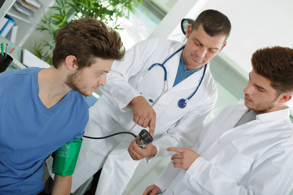 medico sta misurando la pressione sanguigna di un giovane paziente - Foto, immagini