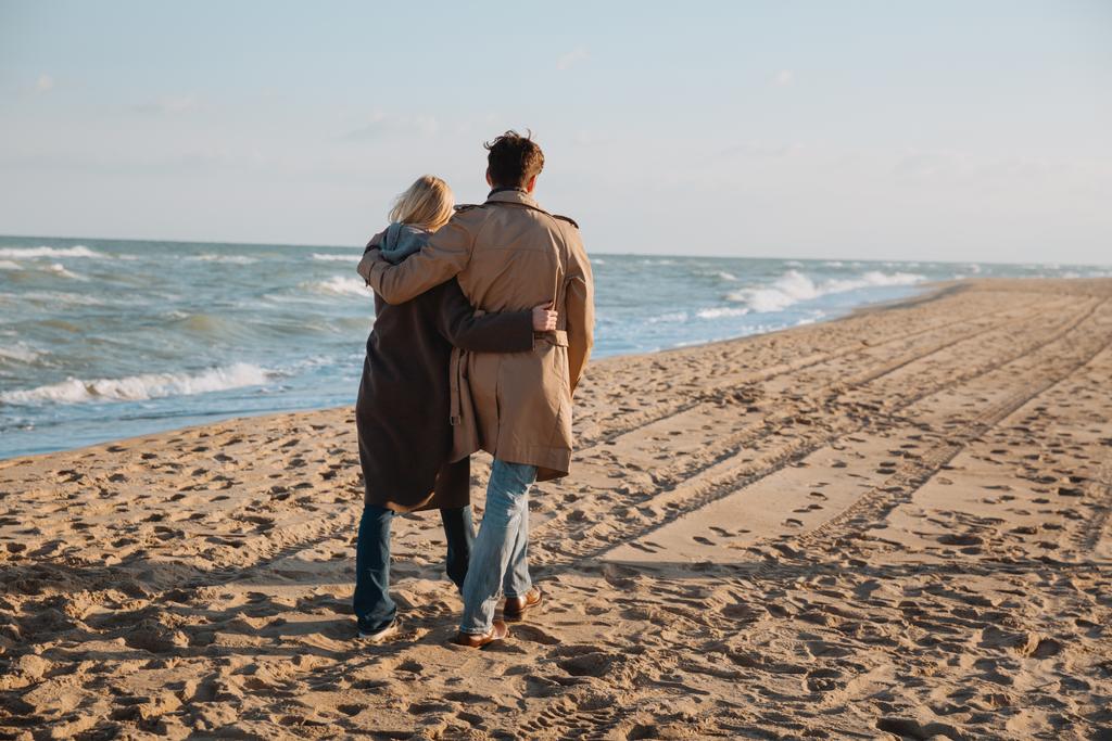 casal abraçando e andando à beira-mar
 - Foto, Imagem