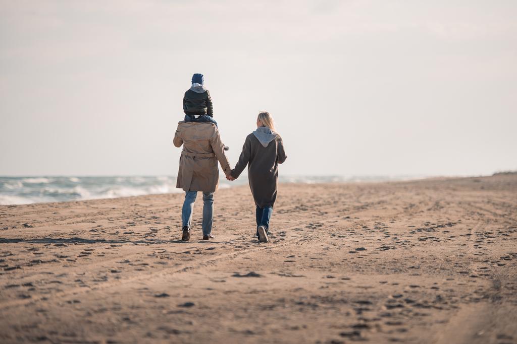 pais e filho andando na praia
  - Foto, Imagem