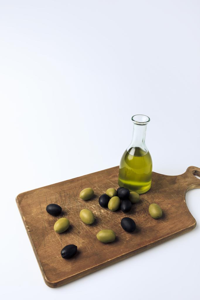 Bottle of olive oil and olives on board - Photo, Image
