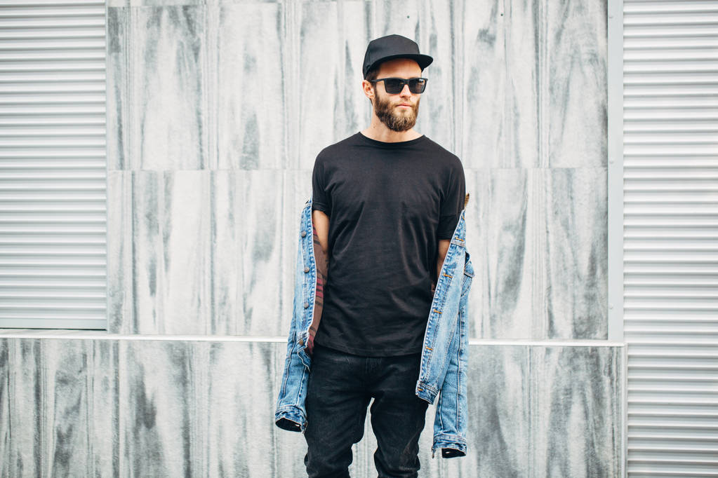 Uomo hipster che cammina indossando jeans neri, t-shirt e baseball
  - Foto, immagini