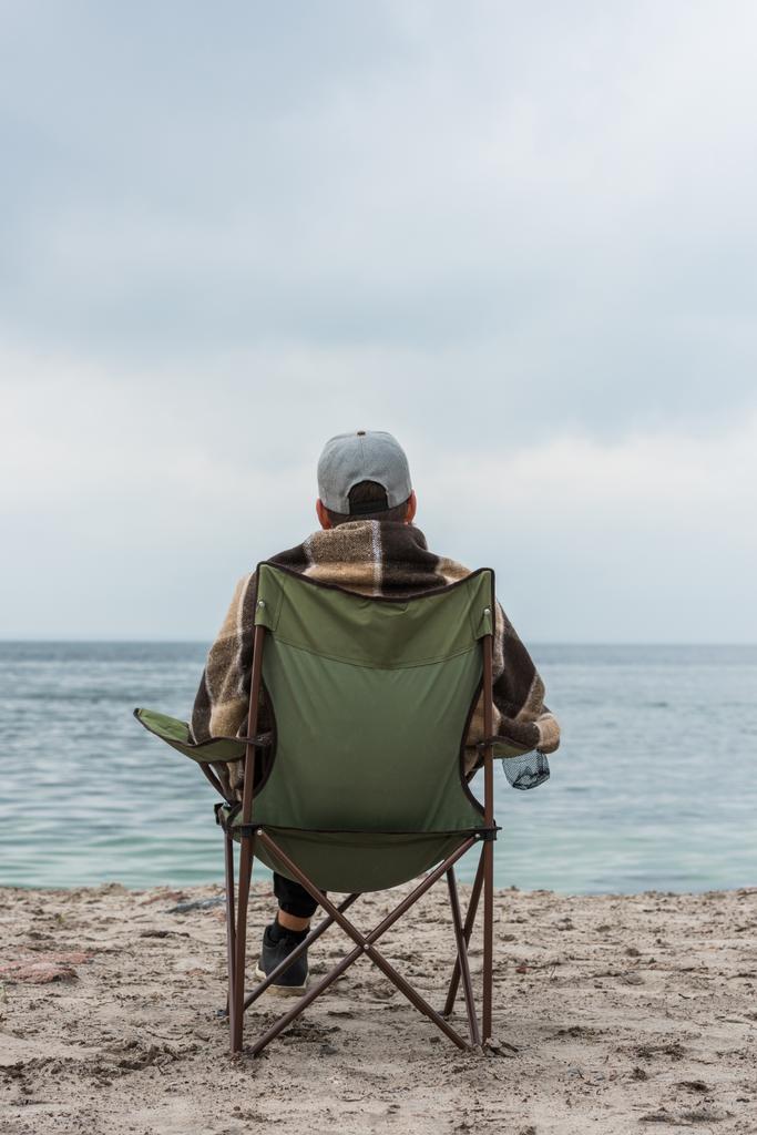 hombre sentado en la silla a la orilla del mar
 - Foto, imagen