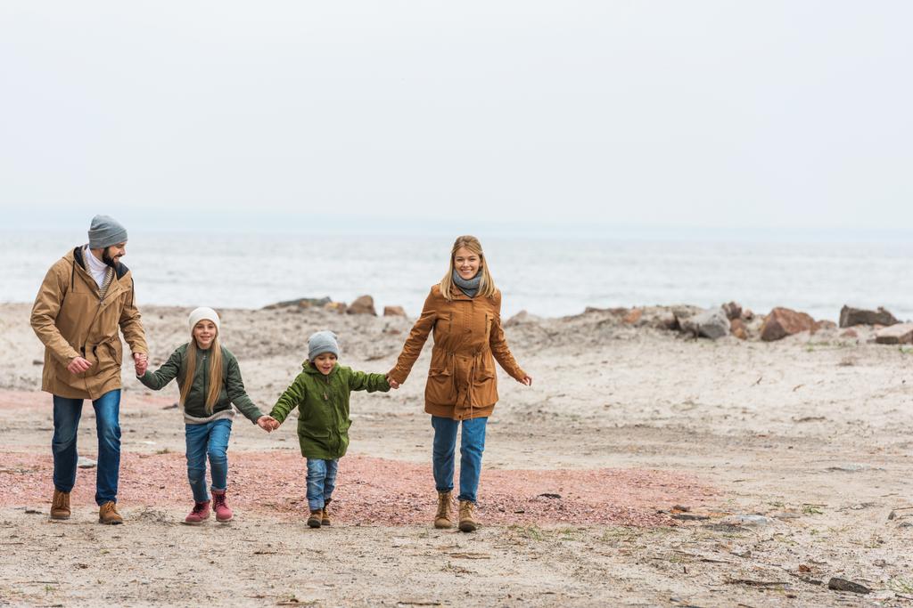 familie hand in hand en wandelen door de seashore - Foto, afbeelding