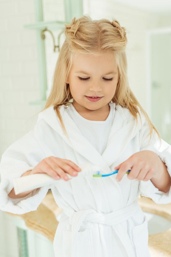 child in bathrobe brushing teeth - Photo, Image