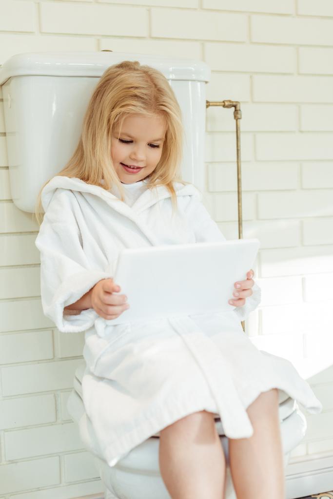 Kind mit digitalem Tablet auf Toilette - Foto, Bild
