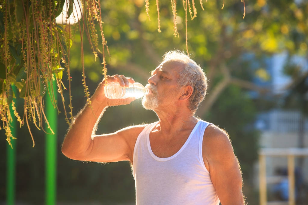 Muž drží láhev s vodou v parku - Fotografie, Obrázek