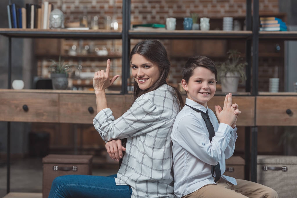 Äiti ja poika poseeraavat sormiaseiden kanssa
 - Valokuva, kuva