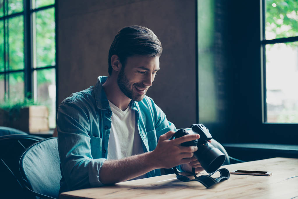 Cheerful dreamy brunet hipster traveller is watching his shoots  - Photo, Image