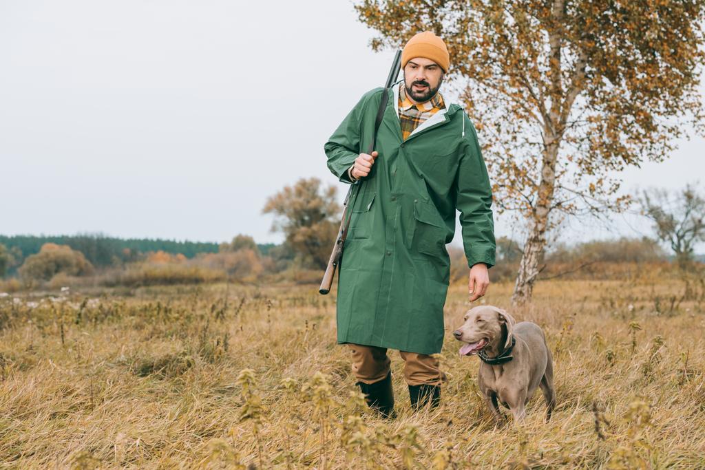 köpek ve silah ile yürüyen adam - Fotoğraf, Görsel