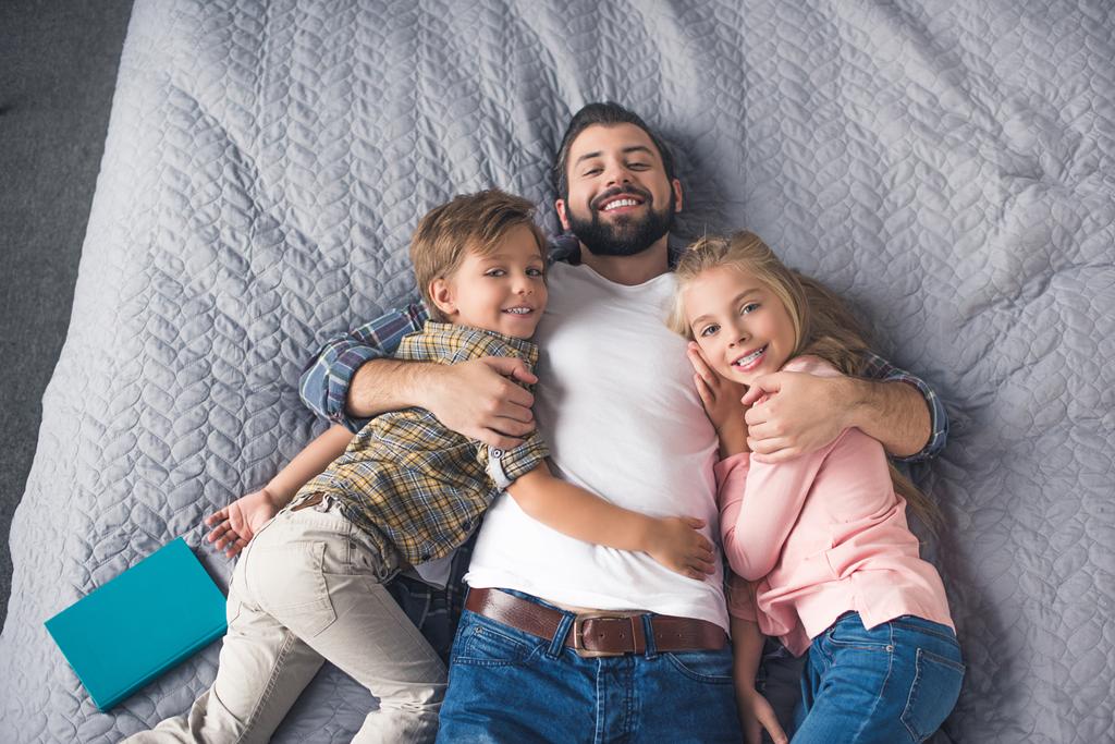 Vater und Kinder ruhen sich im Bett aus - Foto, Bild